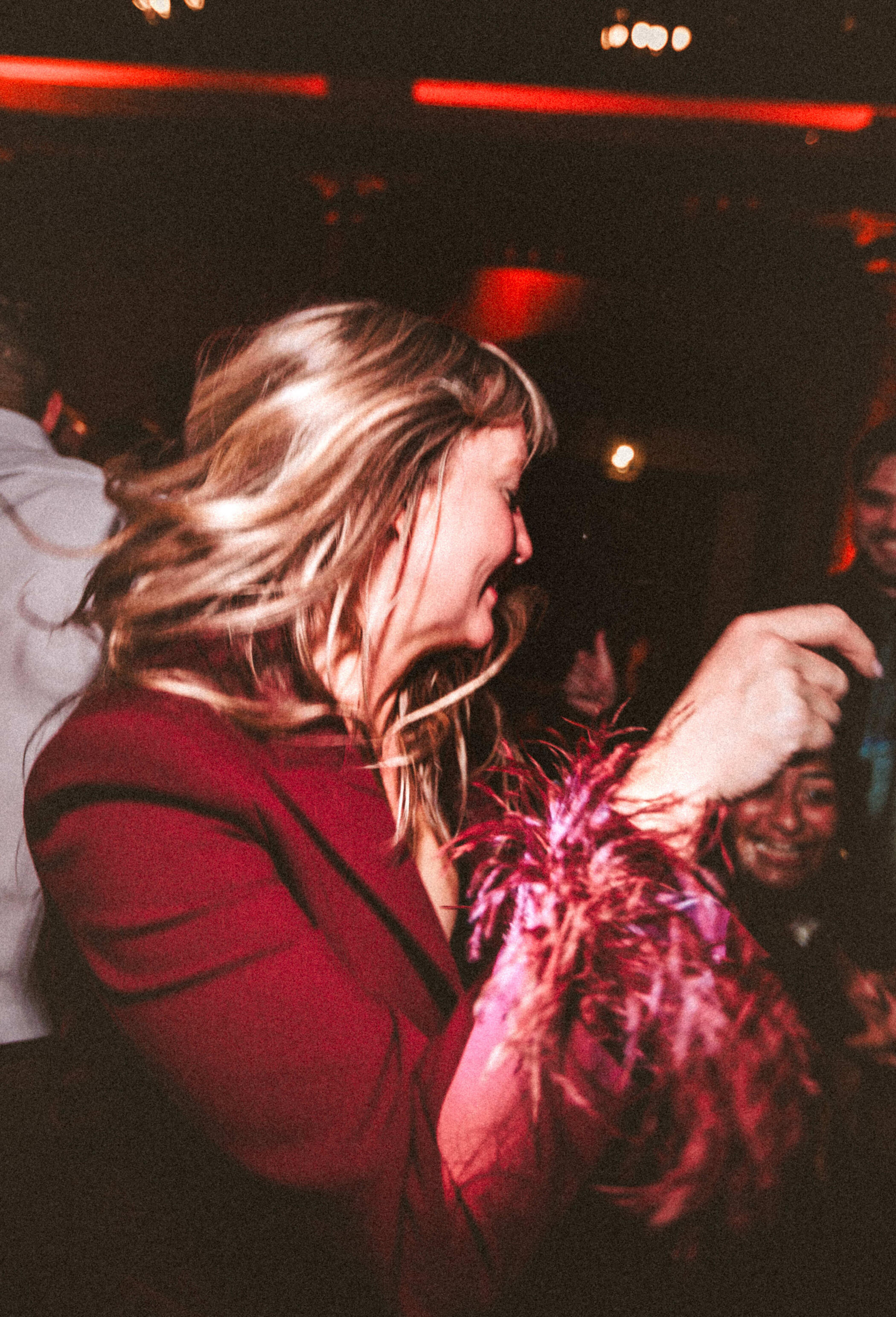 A wedding guest dancing under warm red lights